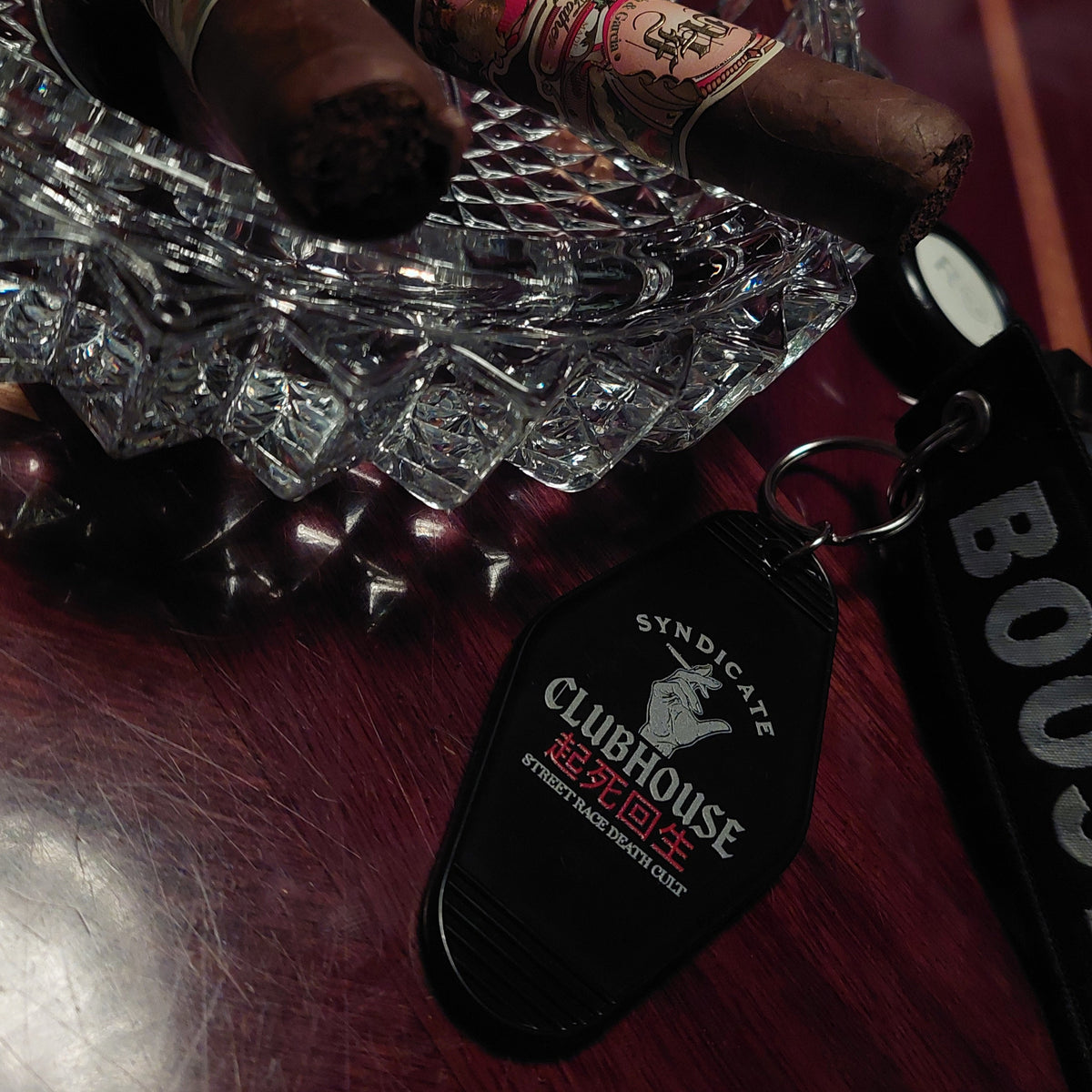 Black Clubhouse Motel 6 keyring photographed beside a cigar and ashtray
